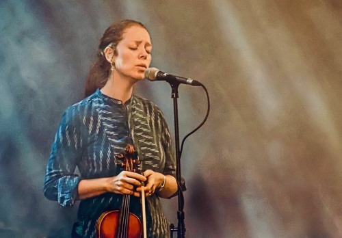Vocalist singing sacred sound with violin under stage light